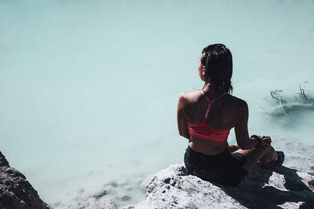 山白天 穿着粉色运动胸罩的女人坐在靠近水体的岩石上湖岩石阿尔卑斯山