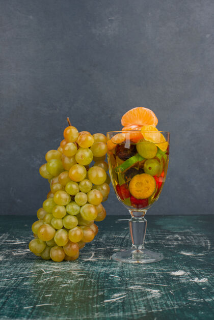 柑橘大理石桌上摆着一杯水果和一簇葡萄罐子葡萄沙拉