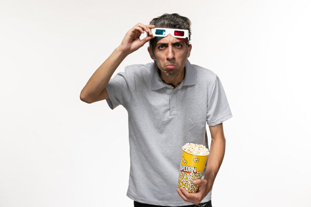 年轻男正面图年轻男性手持爆米花包 戴着d墨镜在白色表面爆米花孤独电影