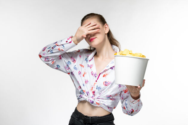 电影院正面图：年轻的女性拿着篮子 拿着薯片 在白色的表面上看电影前面土豆电影