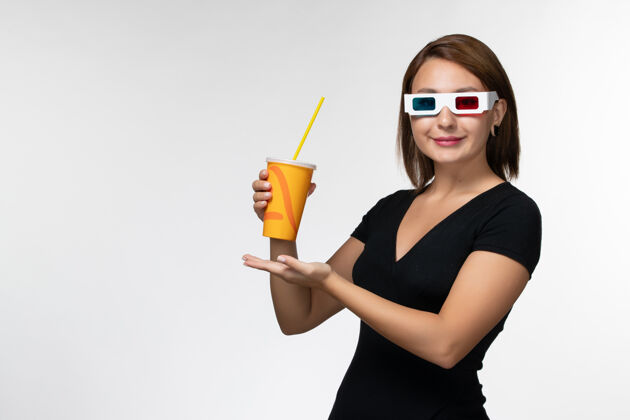 年轻的女性正面图白色表面上戴着d墨镜拿着苏打水的年轻女性太阳镜电影电影