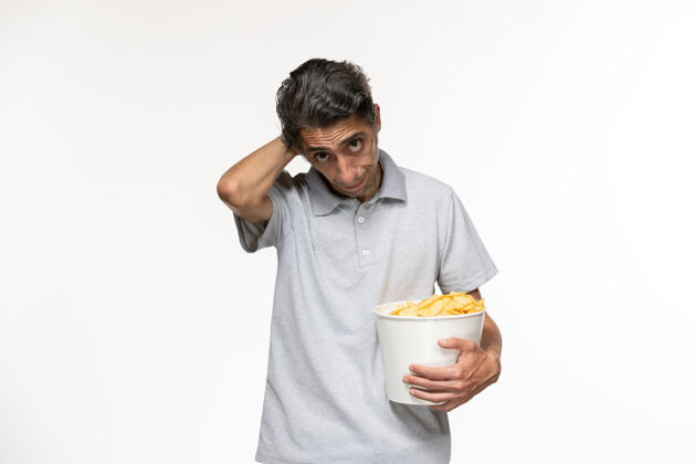 孤独正面图年轻男性一边吃薯片一边在白色的表面看电影电影电影院男