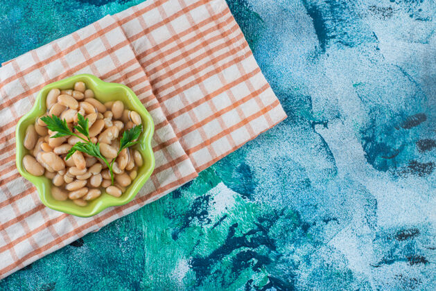 风味一碗烤豆放在茶巾上 蓝色背景烘焙碗美味