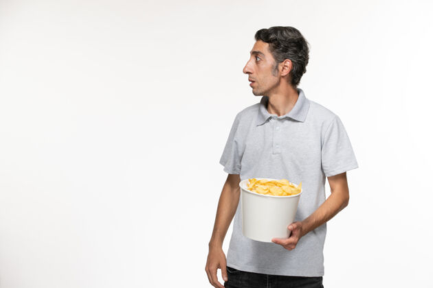 电影院正面图：年轻男性在浅白的表面上吃薯片服务员孤独电影