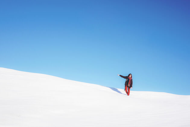 极简主义白天站在白色雪地上的女人蓝天意大利斜坡