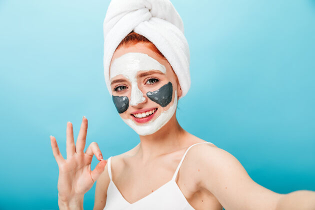 面膜戴着口罩的女人 表情很好 笑着说女模特一边做水疗一边自拍大笑毛巾完美皮肤