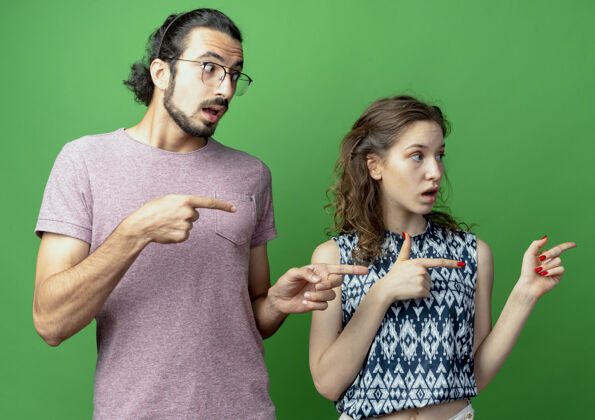 目录年轻的一对男女看起来很困惑 他们用食指指着绿墙那边夫妇指向年轻