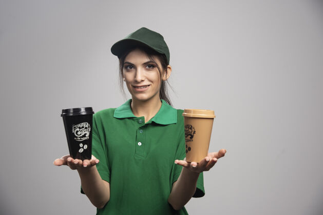 承运人穿着绿色制服拿着咖啡杯的女送货员杯子工人工作