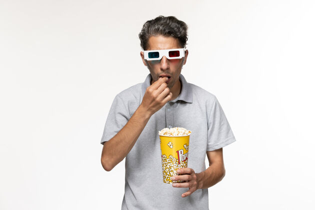 啤酒正面图年轻男性戴着d型太阳镜在白色表面吃爆米花孤独容器年轻男性