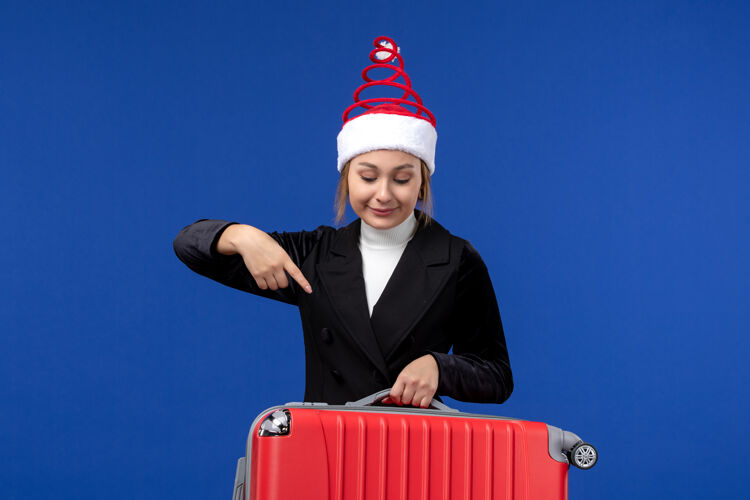 西装正面图年轻女子背着红包在淡蓝色的墙上度假旅游的女人人工人携带