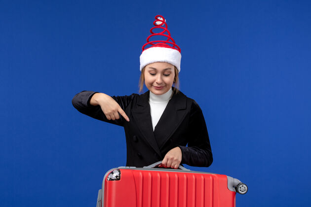 西装正面图年轻女子背着红包在淡蓝色的墙上度假旅游的女人人工人携带