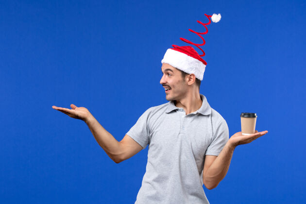 人正面图年轻男子拿着咖啡杯在蓝色的墙上情绪新年男子杯子火炬男性
