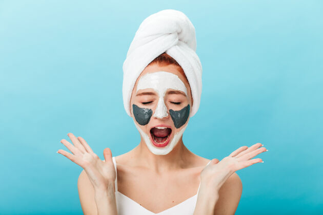 健康情绪化的女孩在做护肤品治疗时尖叫的前视图蓝色背景上隔离面具的神奇女士的摄影棚照片自然擦洗水疗