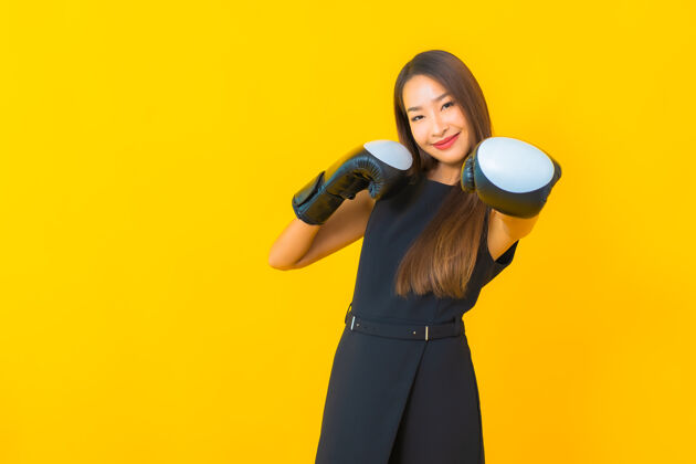 竞争在黄色背景上画一个戴拳击手套的美丽的亚洲女商人运动成功亚洲人