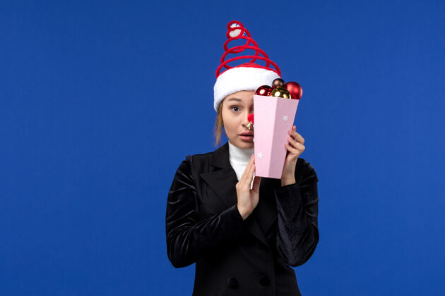 肖像正面图：年轻女性在蓝色墙壁上用玩具遮住脸 感慨新年假期圣诞节商人封面