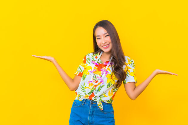 女人美丽的亚洲年轻女子穿着彩色衬衫在黄色墙上的肖像传统乐趣旅游