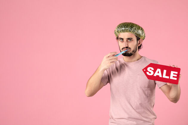 牙齿正面图年轻的男性正在清洁他的牙齿和销售在粉红色背景上的铭牌光滑标签美容