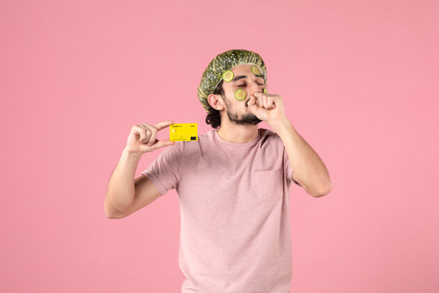 淋浴帽正面图：戴着面具的年轻男子 手持粉色背景的银行卡衣服脸持有