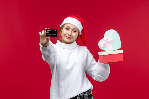风景正面图红色背景上的年轻女性 带着银行卡和礼物礼物欢乐红色