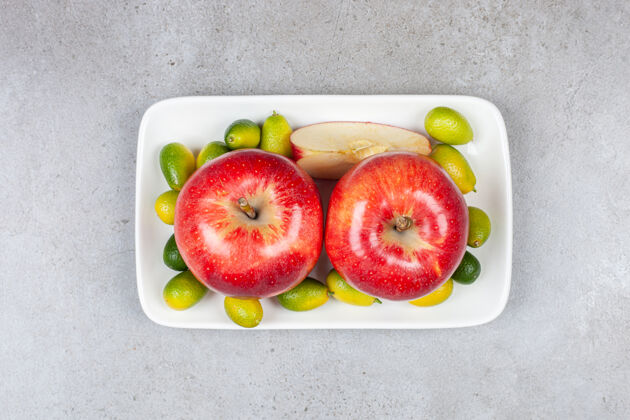 水果白板上一堆金橘和熟苹果的俯视图新鲜部分绿色