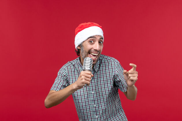 人正面图红色背景上手持麦克风的年轻男性前面情绪圣诞