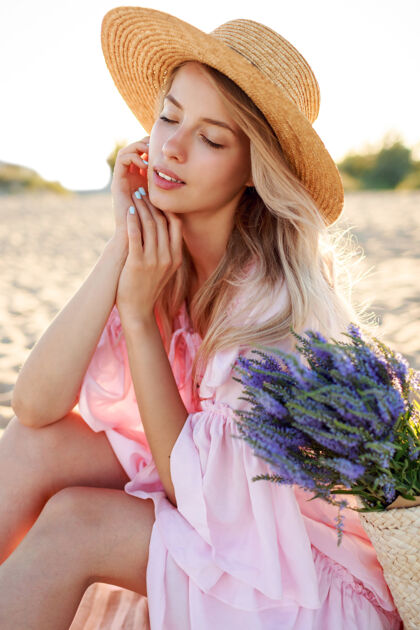 减肥户外生活写真优雅的白人女子坐在阳光明媚的海滩上靠近海洋戴草帽自然背景水果休息沙滩