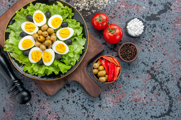 蔬菜俯视图美味的煮蛋和绿色沙拉橄榄和西红柿在轻背景早餐餐茶