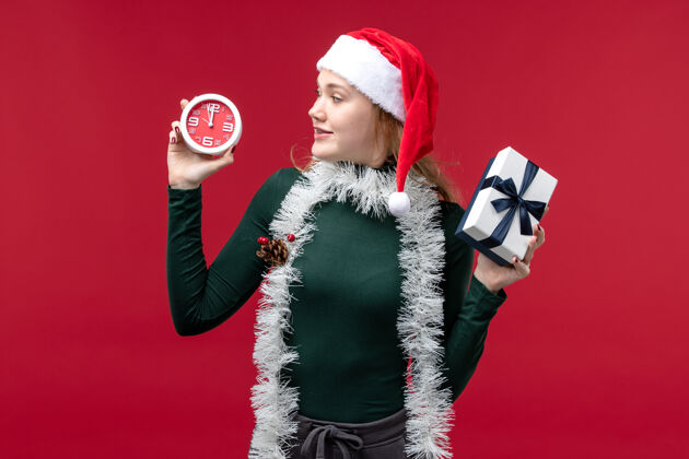 人正面图：年轻女性 红色背景上有带时钟的礼物圣诞节姿势年轻女性