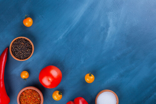 盐美味的新鲜蔬菜和各种调味品在蓝色的表面上顶视图蔬菜地