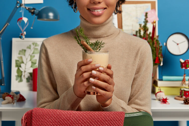 圣诞节一个穿着棕色套头衫的女人拿着美味的传统圣诞饮料 里面装满了肉桂和云杉桌子自制装饰