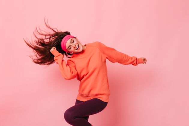 健身粉红色墙上的年轻黑发女子健身照80后风格运动健美操