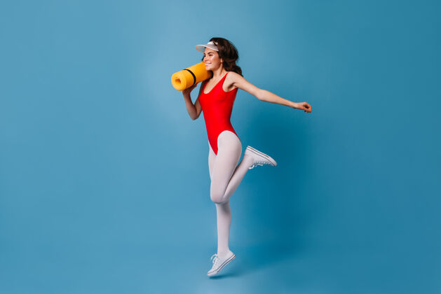 肖像健康强壮的80后年轻女子在蓝墙上做运动健美操运动服移动