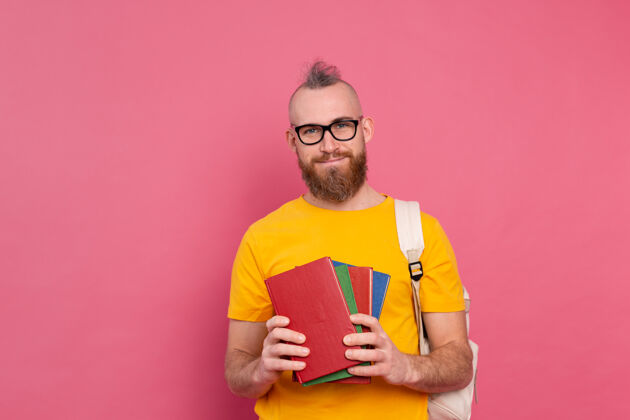 聪明一个留着胡子 背着书包 拿着书 穿着休闲装 快乐的成人学生粉红大学人