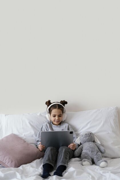 孩子小女孩在床上用耳机用平板电脑平板电脑科技室内