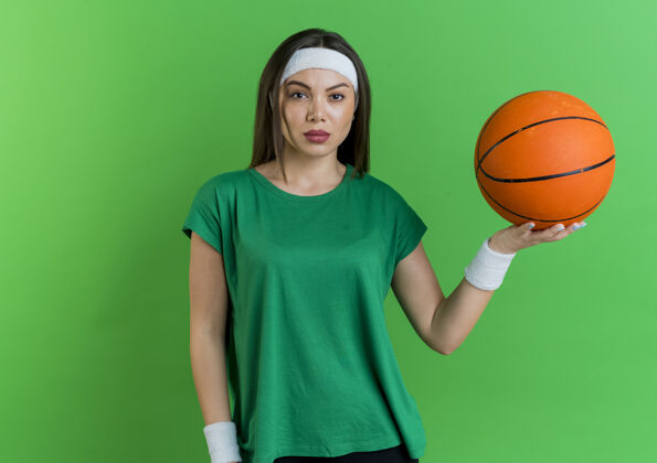 穿自信的年轻运动女性戴着头带和腕带拿着篮球看头带篮球女子
