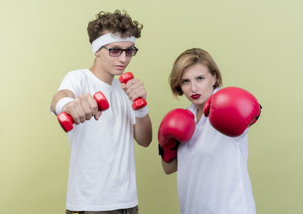 手套一对年轻的运动型情侣 戴着拳击手套 拿着哑铃站在女友旁边 在灯光下摆姿势轻年轻运动