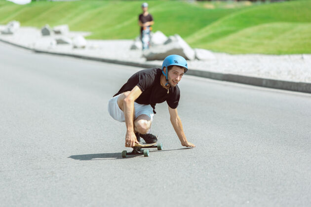 男人在阳光明媚的日子里 滑板运动员在城市的街道上玩花样极限动作休闲