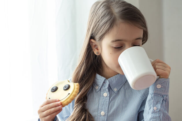 肖像一个小学生正在吃早餐 早餐里有牛奶和笑脸形状的有趣饼干饼干饮料童年