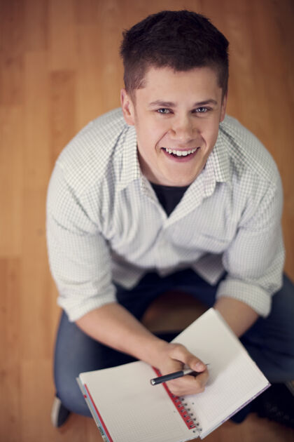 成功坐在地板上的年轻学生笔记本学习棕色头发