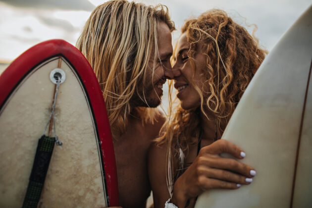 爱快乐的男人和女人亲吻一对夫妇拿着冲浪板冲浪一起男性