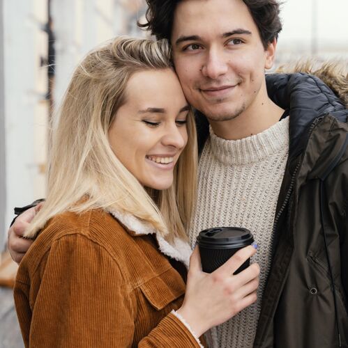 一起年轻夫妇在户外享受一杯咖啡拥抱情侣年轻