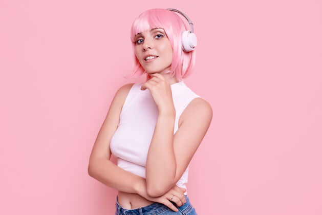 美丽粉红头发的美女肖像在耳机里欣赏音乐放松音频耳机