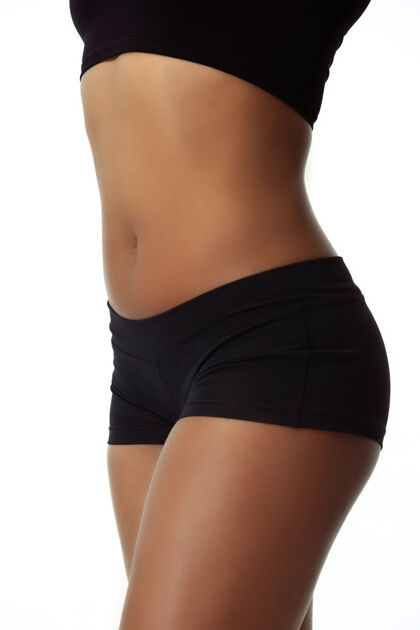 健身腹部和臀部苗条的晒黑女人的身体隔离在白色的墙壁上健康运动躯干