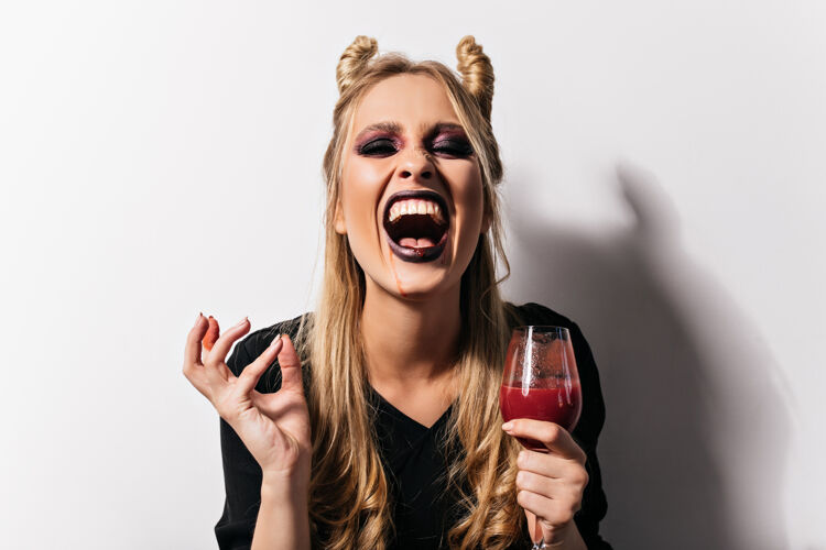 僵尸在万圣节派对上 快乐的金发吸血鬼喝着血肖像化妆舞会女巫