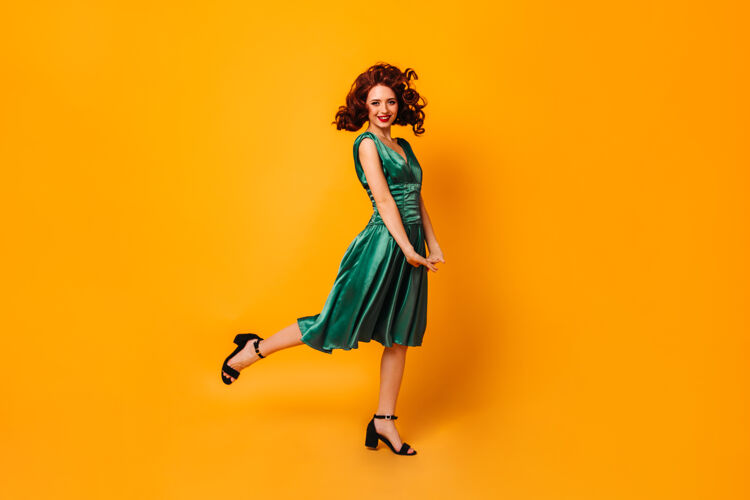 表情一只脚站着一个穿着绿色裙子的兴奋的健康女孩黄色空间里翩翩起舞的优雅女士的全貌魅力年轻人淑女