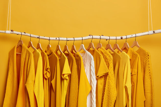 选择一套亮黄色的衣服和一件白色的毛衣挂在衣架上可供穿着的女装系列适合温暖和炎热天气的各种服装商店衣架夹克