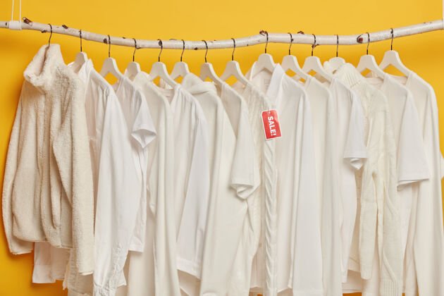 休闲清仓出售白色衣架上的黄色背景隔离选择时尚女装服装手销售