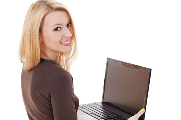 坐着在笔记本电脑上工作的年轻女人电脑转身白色背景