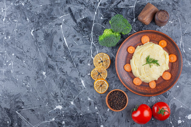 番茄把土豆泥和胡萝卜片放在盘子里 放在蓝色表面的蔬菜和香料碗旁边营养美味新鲜