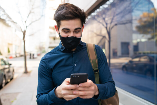 人年轻人在街上户外散步时使用手机的照片新的正常生活方式概念城市概念冠状病毒肖像短信